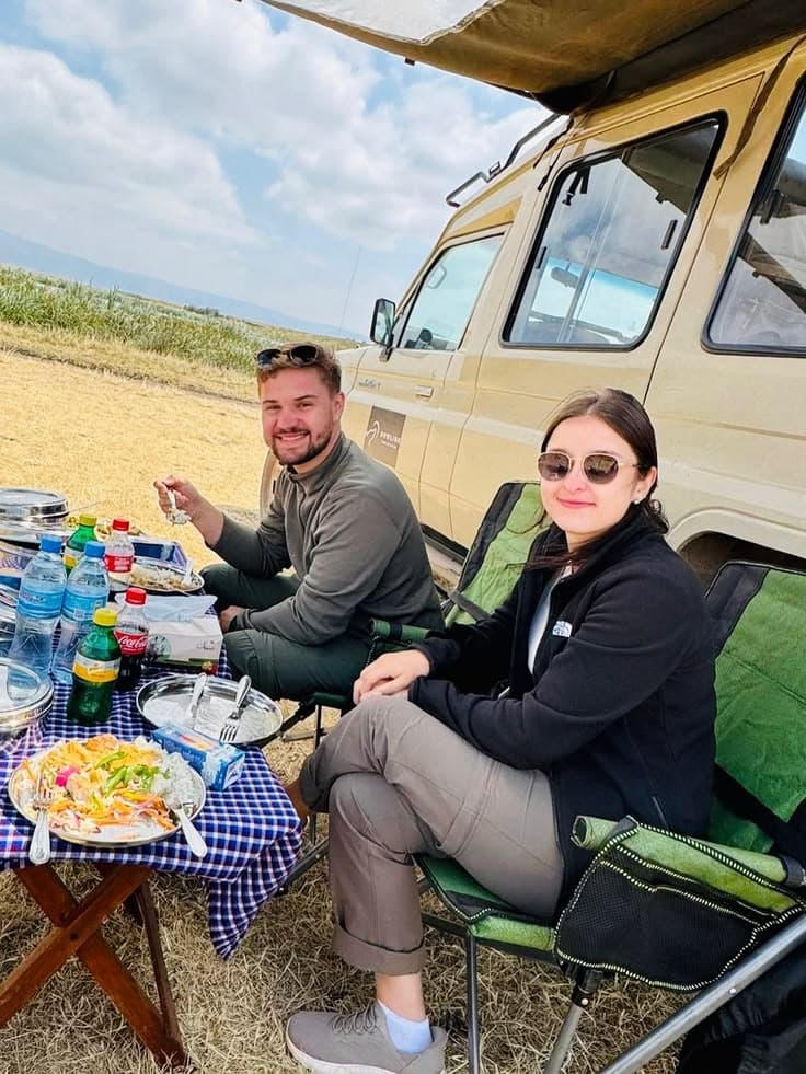 Sundowner drinks at sunset with safari vehicles nearby